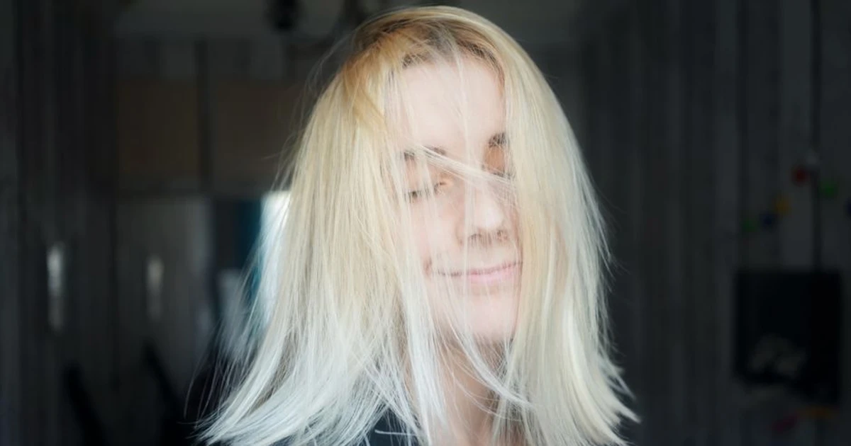 Bleke hårfarge: kvinne med langt bleket blondt hår, iført rutete sort genser.