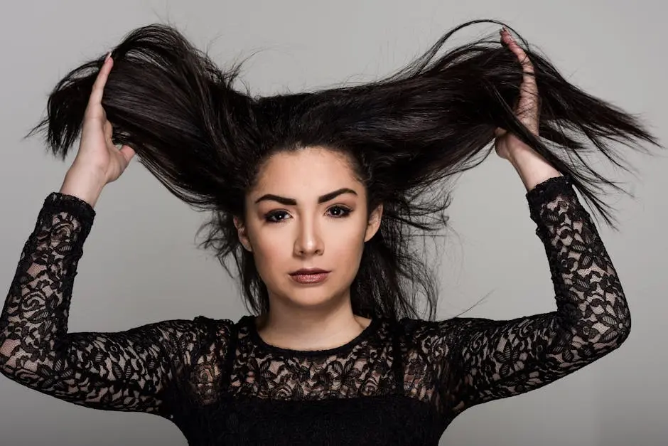 Portrait of a woman in lace attire, holding her hair up with confidence. Studio shot.