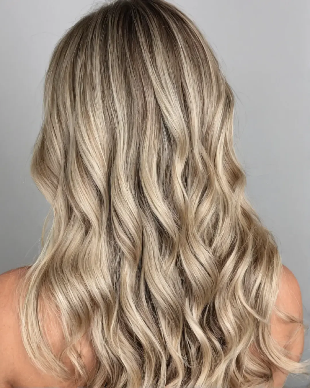 Langt blondt hår med beach waves og myk balayage-overgang.